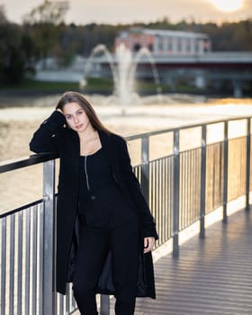 Portrait of a girl on a bridge near a pond in a city park against the backdrop of fountains