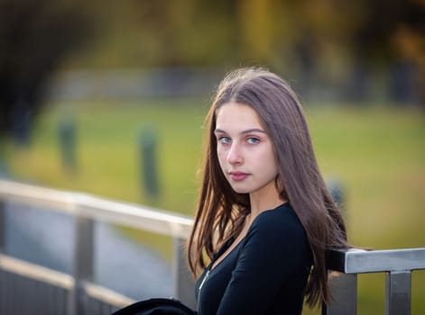 A girl poses on a bridge in a city park