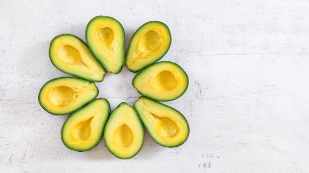 Top down view, 8 avocado halves arranged in circle on white board, banner with space for text right