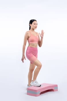 Vigorous energetic woman doing exercise at on studio short isolated background with cardio aerobic step workout. Young athletic asian woman dexterity and endurance training session concept.