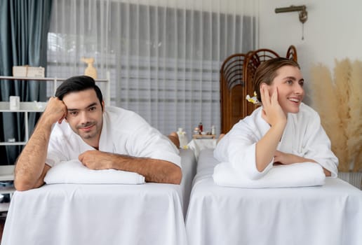 Caucasian couple customer enjoying relaxing anti-stress spa massage and pampering with beauty skin recreation leisure in day light ambient salon spa at luxury resort or hotel. Quiescent