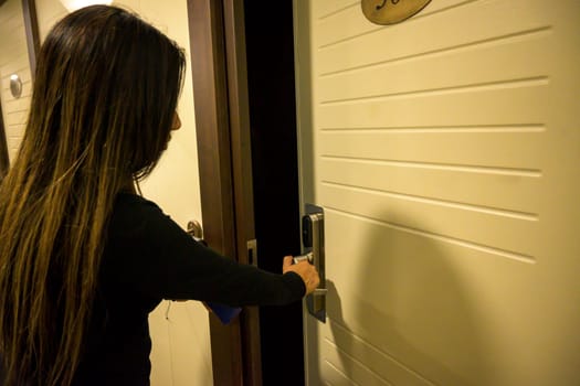 Latin Woman opens a door with a keycard in a hallway, key electronic lock, hotel room, holidays in mallorca, spain.