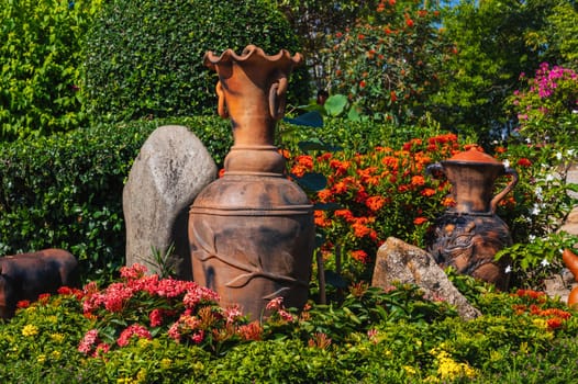 Asian garden is decorated with a stone and a clay jug in summer in Asia
