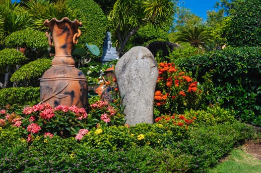 Asian garden is decorated with a stone and a clay jug in summer in Asia