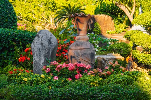 Asian garden is decorated with a stone and a clay jug in summer in Asia