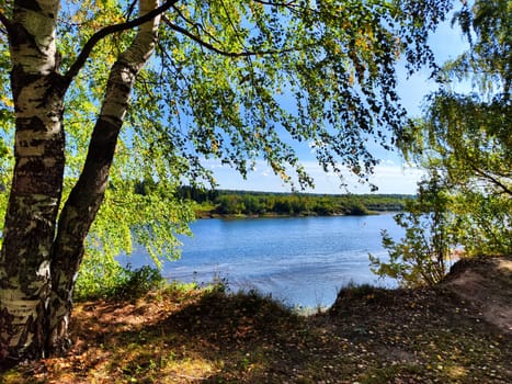 The picturesque river flows gently, surrounded by lush greenery and bathed in sunlight, evoking a peaceful spring atmosphere.