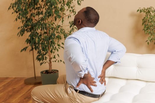 Young man suffers from back pain in the bedroom, Osteochondrosis of the lumbar region, emergency care,