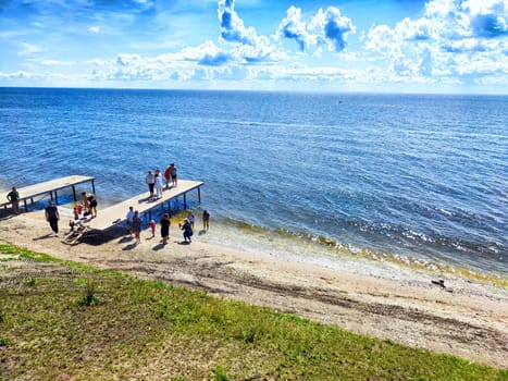 Groups of individuals gather on docks by the water's edge, soaking in the sun and enjoying the clear blue skies on a warm day.