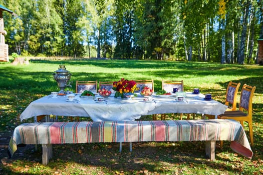 A beautifully arranged table ready for outdoor dining with vibrant flowers and rustic chairs.