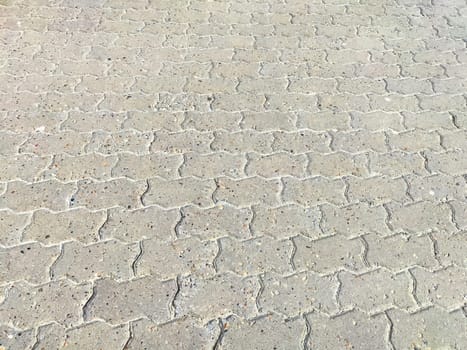 A close-up view of concrete pavement surface, showcasing interlocking pavers arranged in a diagonal pattern