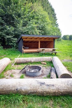 A quiet outdoor campsite featuring a wooden shelter, picnic table, and campfire pit. Ideal for camping, featuring a natural setting surrounded by lush greenery in demark