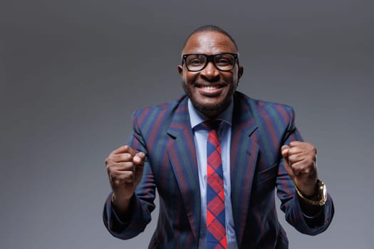 Man business in a suit happy smile with teeth raised hands up clenched fists on a gray background. The joy of winning in business