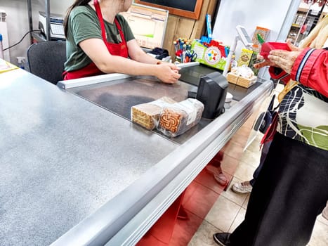 Sovetsk, Russia - September 25, 2024: Buyers checking out at a bustling store while the seller processes transactions at the checkout counter