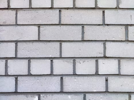Smooth gray bricks are tightly arranged in a repetitive pattern on the wall.