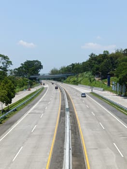 A highway with a bridge over it and cars driving on it. The cars are mostly white and black