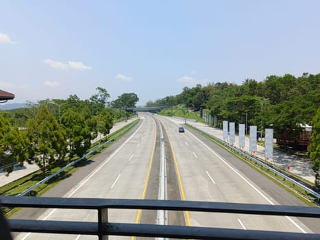 A highway with a bridge over it and cars driving on it. The cars are mostly white and black