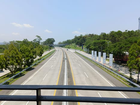 A highway with a bridge over it and cars driving on it. The cars are mostly white and black