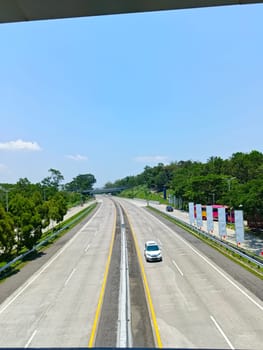 A highway with a bridge over it and cars driving on it. The cars are mostly white and black