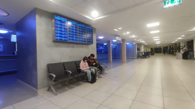 October 26, 2024 Prague Czech Republic Europe, Vaclav Havel Airport, people tourists in the lobby waiting for a flight,two teenagers sitting with mobile phones . High quality photo