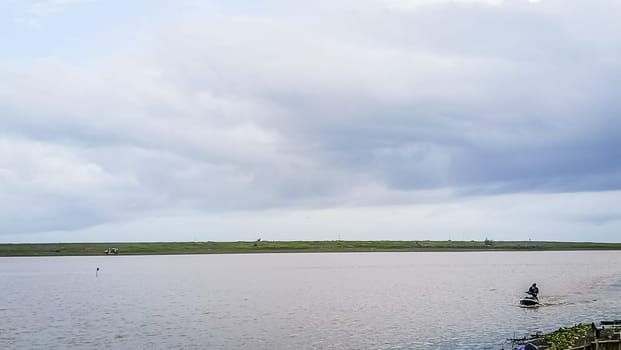A beach with a calm water. The sky is cloudy and the water is calm