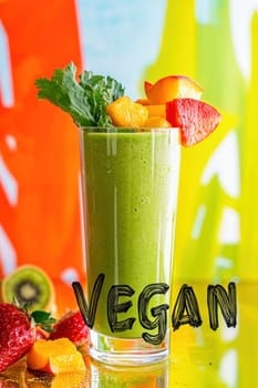 Glass of green vegan smoothie decorated with fresh fruit and celery leaf on colorful background