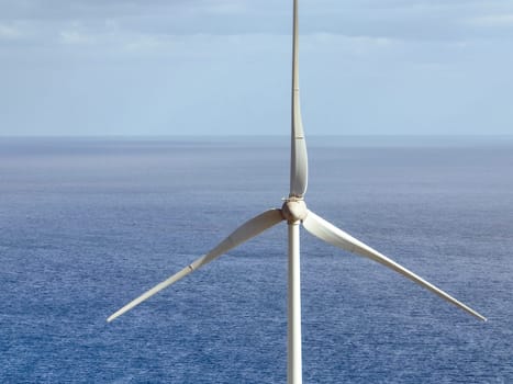 Wind power station with wind turbines, windmill propellers spinning in the wind, closeup view. Development of green ecological alternative energy on the islands of the Atlantic Ocean.