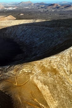 A picturesque volcano crater on the Montana Blanca mountain at sunset against the backdrop of a volcanic landscape with desert, lava formations. Traveling on the island of Lanzarote, Canary Islands.