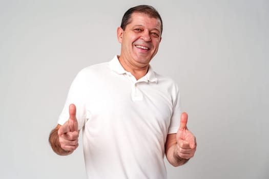 An older man smiling and reaching out with both hands in studio