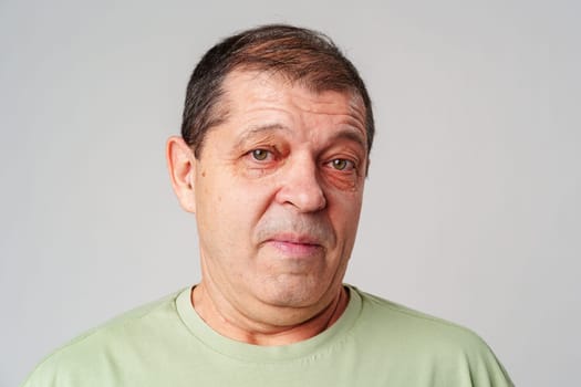Middle-aged man with a thoughtful expression against a plain background close up