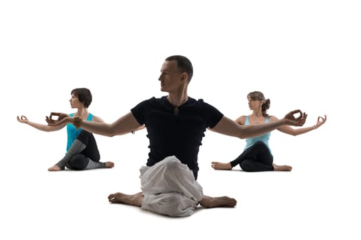 Male trainer and two women doing yoga exercises sitting on the white isolated