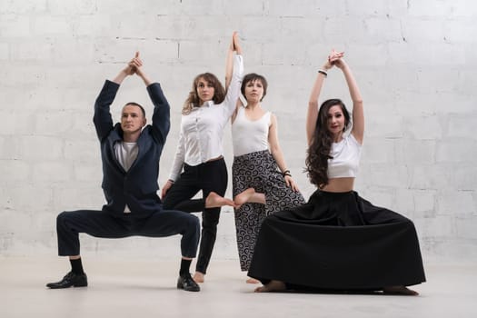 People wearing office clothes doing yoga shot against white brick wall