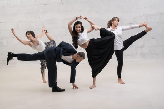 A man and women wearing office clothes doing yoga shot against white brick wall