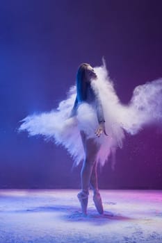 Woman in undrewear and pointe shoes jumping gracefully in a white dust cloud and color light rearview