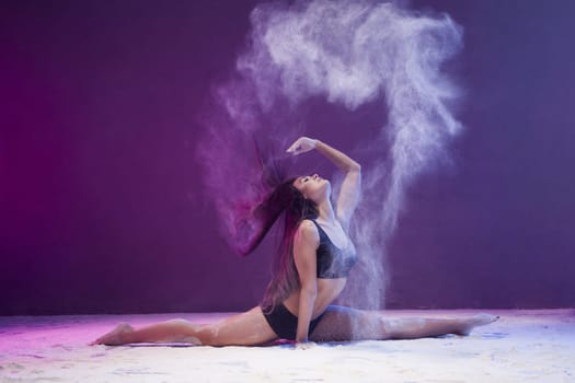 Woman sitting in a split in a white dust cloud profile shot