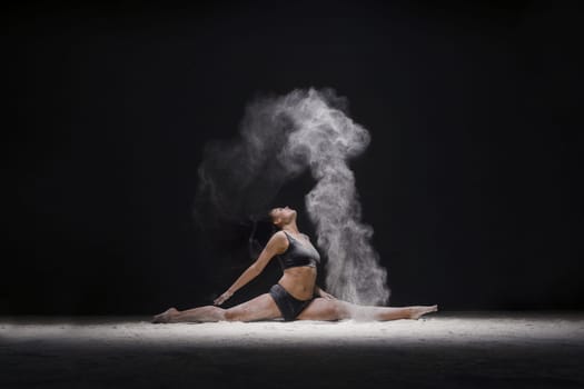Female sitting in a split in a white dust cloud profile view