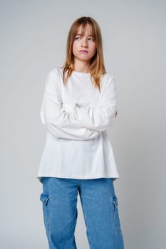 Teen girl stands in casual attire against a plain background, showcasing her thoughtful expression close up