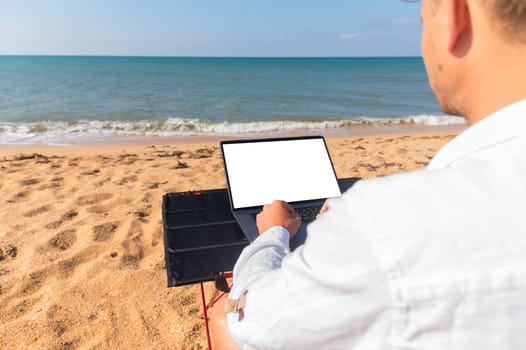 Caucasian young man with laptop on colorful island beach, over shoulder view of isolated screen monitor and hands.
