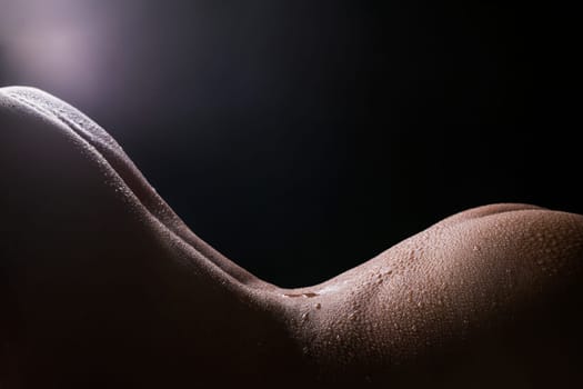Water drops on nude woman body cropped view on black background