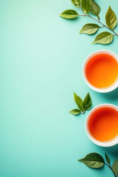 Tea time with two cups of herbal tea and fresh green leaves on a turquoise background creating a relaxing atmosphere