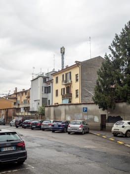 Cremona, Lombardy, Italy October 15th 2024 Parked cars line a residential street in florence, italy, featuring a cell tower against a cloudy sky