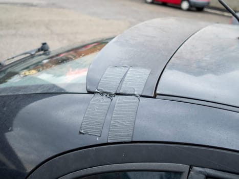 Cremona, Lombardy, Italy October 15th 2024 Close up of a broken car spoiler repaired with duct tape, showing a temporary and makeshift fix
