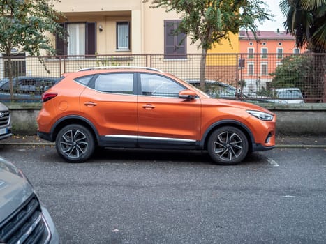 Cremona, Lombardy, Italy October 15th 2024 Orange mg zs suv parked on the side of a residential street, showcasing its sleek design and urban adaptability