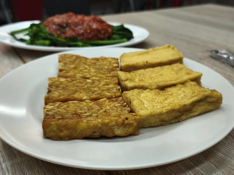 A plate of crispy fried tempeh and tofu, perfect for a vegetarian or vegan meal. The golden-brown color and appetizing aroma make it irresistible.