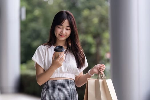 A cute young woman carries a paper bag while shopping at a department store, showcasing a casual and stylish look.
