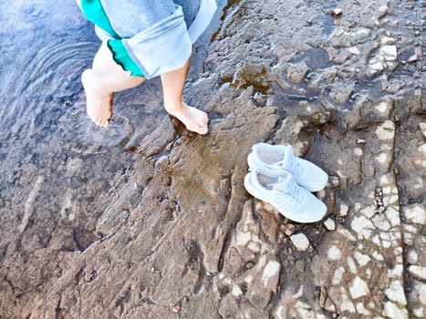 Footsteps in shallow water and shoes resting on dry ground as someone enjoys refreshing moment by the river on a sunny day