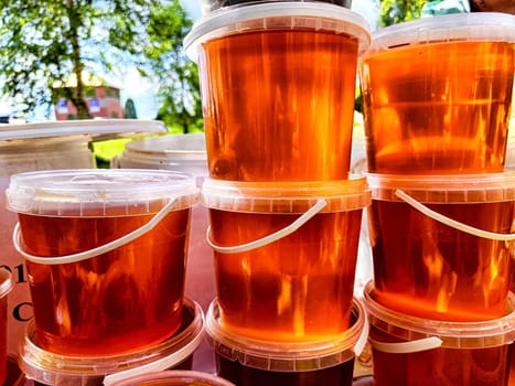 Colorful jelly or honey cups are neatly arranged in a stack at bustling outdoor market on a sunny day