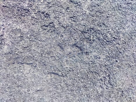 Gray gravel surface features small stones and uneven textures in bright daylight.