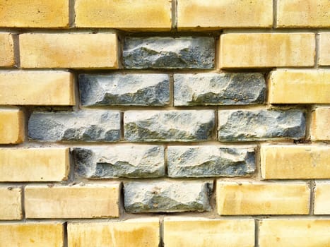 A captivating brick wall showcases a unique combination of smooth yellow bricks and rough gray stones, offering a perfect area for text or designs.