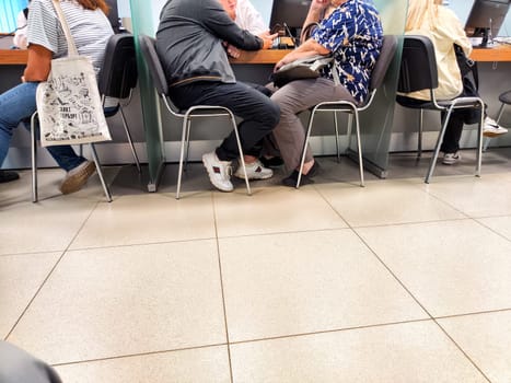 Kirov, Russia - September 18, 2024: Customers sit in a bank hall, waiting patiently for available managers to handle their financial needs on a busy day.