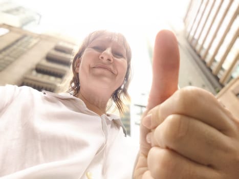 A traveler enjoys her adventure, smiling for a selfie in a bustling urban area. The adventures of middle-aged female tourist on a trip